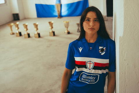 A model wearing the blue U.C. Sampdoria home shirt featuring the classic horizontal band across the chest.