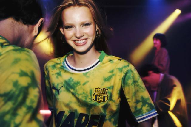 A model wears the yellow and green tie-dye U.S. Sassuolo 2025/26 third shirt in a campaign photo.