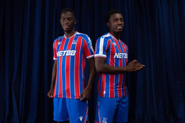 Two players posing in the Crystal Palace FC home shirt.