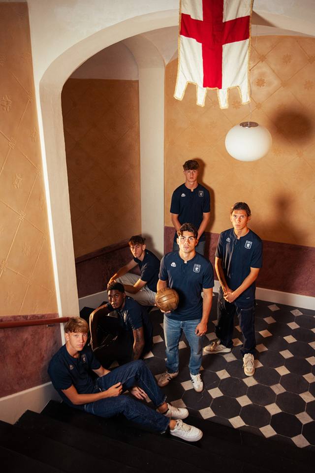 A group of models on a staircase presenting the Genoa CFC dark blue third shirt.