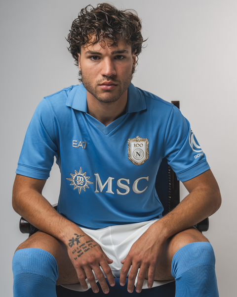 A promotional studio photo of a player wearing the SSC Napoli home shirt by EA7.