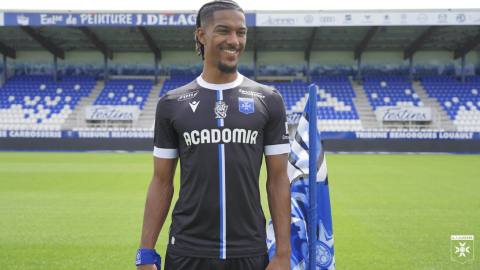 AJ Auxerre player presenting the black 2023/24 away shirt at the stadium.