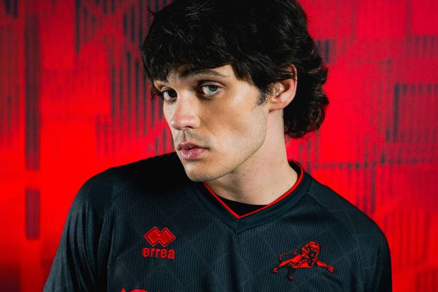 A model wears the black and red Millwall FC 2025/26 third shirt by Erreà.