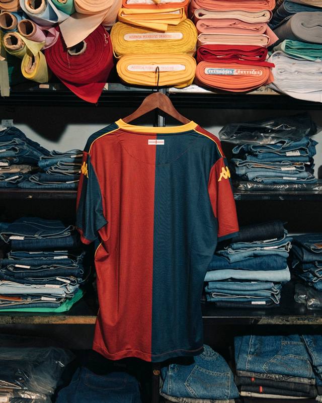The back of the Genoa CFC 2025/26 home shirt on a hanger inside a tailor's workshop.