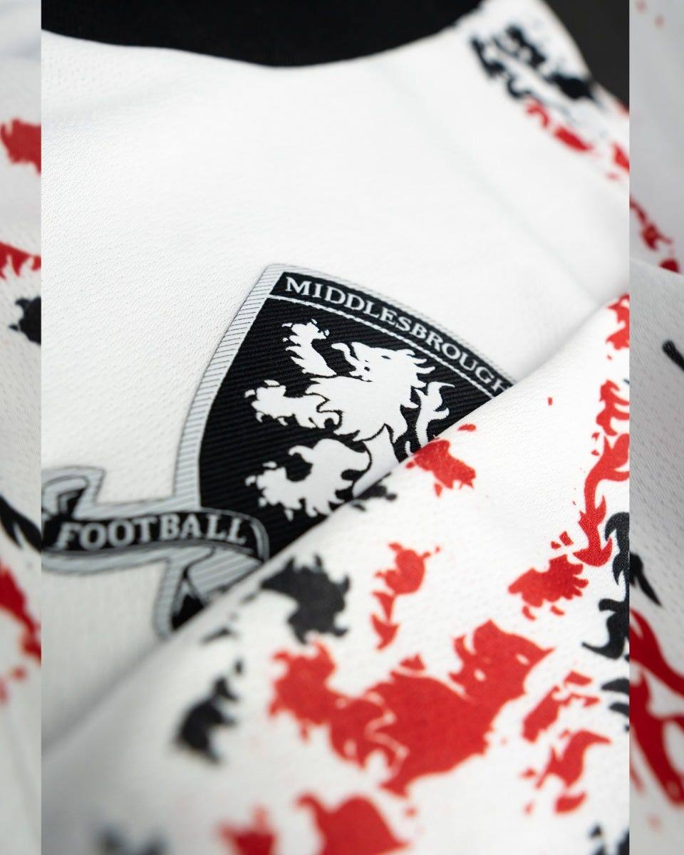 A close-up detail of the Middlesbrough FC crest on their white third shirt.