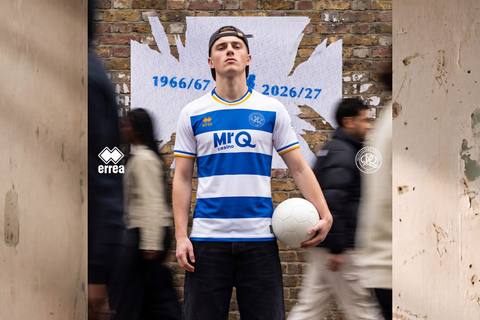 A model presents the Errea Queens Park Rangers 2026/27 home shirt, featuring classic blue and white hoops with gold trim on the collar and sleeves.
