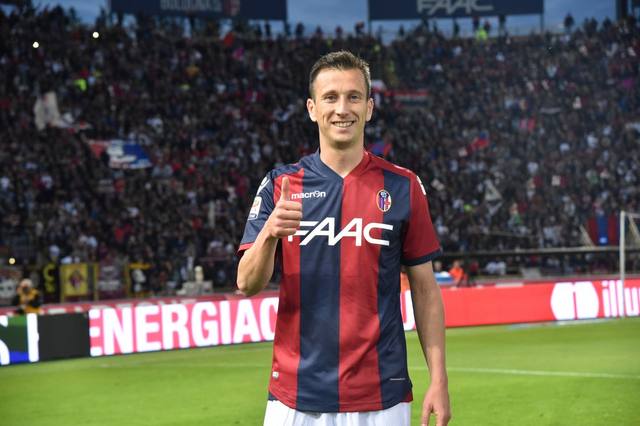 Bologna FC player posing in the 2016/17 home shirt on the pitch.
