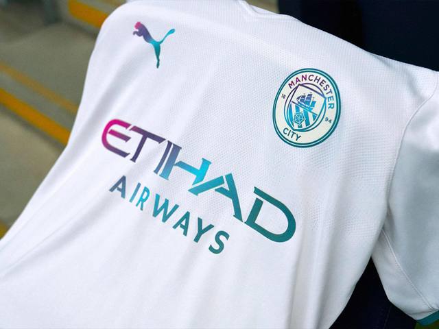 A close-up view of the Manchester City 2021/22 away shirt, featuring iridescent logos and details.