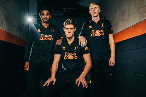 Dundee United players model the black and orange third shirt.