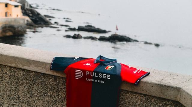 A Genoa CFC home shirt draped over a stone ledge with the sea in the background.