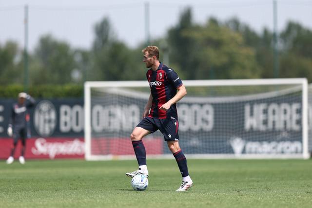 A Bologna FC player on the training pitch wearing the club's red and blue home shirt.