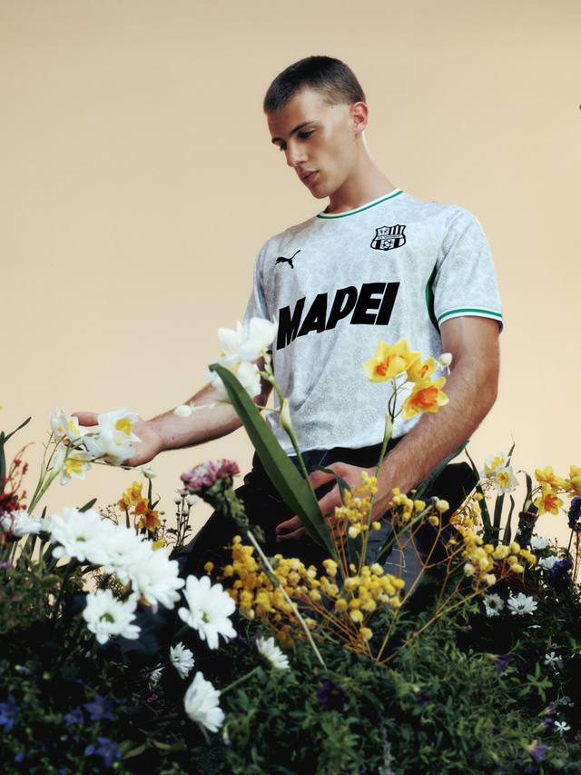 A model presents the U.S. Sassuolo 2026/27 away shirt in a stylized photoshoot with flowers.