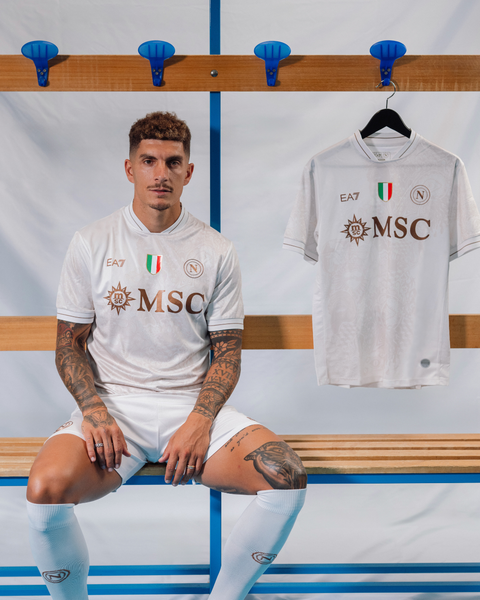 Giovanni Di Lorenzo wearing the white SSC Napoli 2025/26 away shirt next to another hanging on a rack.