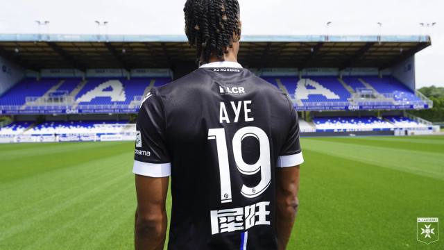 The back of the black AJ Auxerre 2023/24 away shirt, worn by player Ayé with number 19, in the club's stadium.