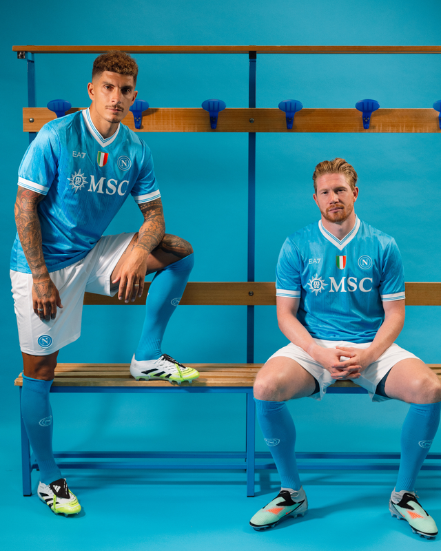 Two players posing in a locker room setting wearing the SSC Napoli 2025/26 home shirt.