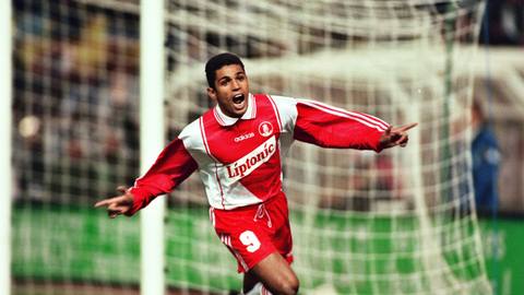 A player celebrating on the pitch in a classic red and white AS Monaco home shirt with a Liptonic sponsor.