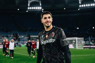 A Bologna FC 1909 player wearing a dark patterned shirt on the pitch after a match.