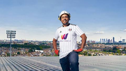 A man wearing the Fulham FC 2021/22 home shirt during a campaign shoot on a stadium roof.