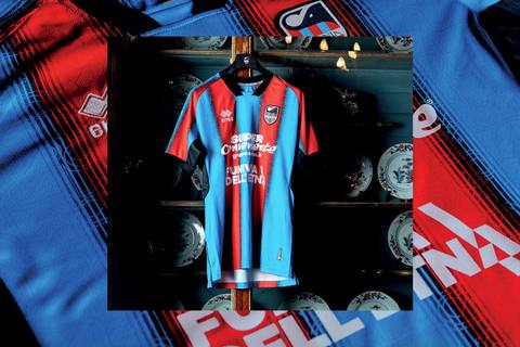 The Catania FC home shirt featuring traditional red and light blue vertical stripes, displayed on a hanger inside a cabinet.