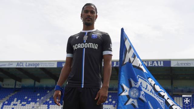 A player posing in the AJ Auxerre 2023/24 away shirt at the stadium.