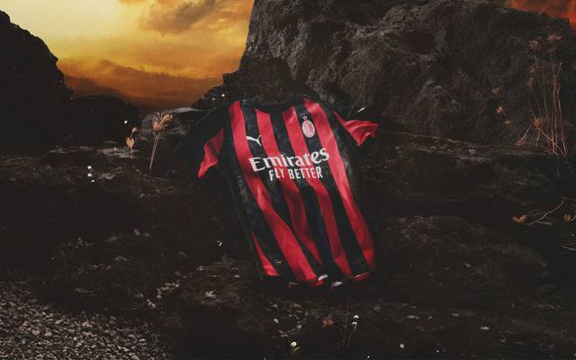 AC Milan home shirt featuring classic red and black stripes, presented on dark volcanic rocks.