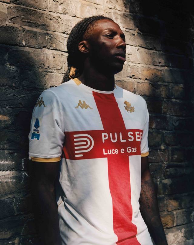 A player wearing the Genoa CFC away shirt with a red cross design on a white base.