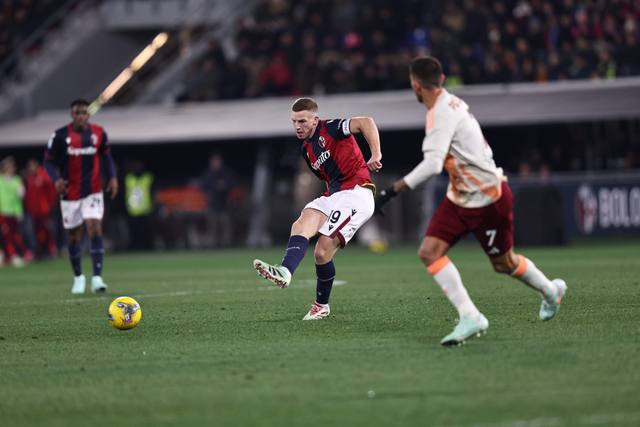 Bologna FC players on the pitch wearing their classic red and blue striped home shirt featuring the Saputo sponsor.