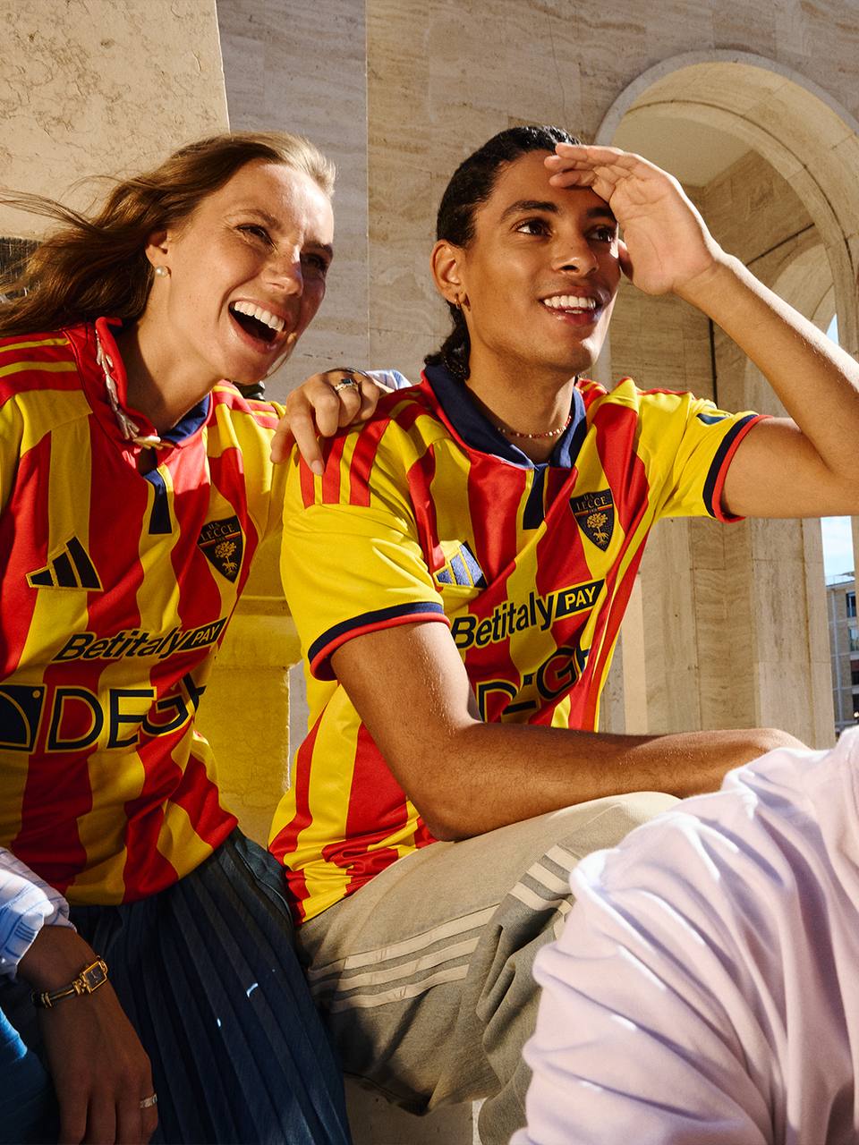 Models present the red and yellow striped U.S. Lecce home shirt in a campaign photo.
