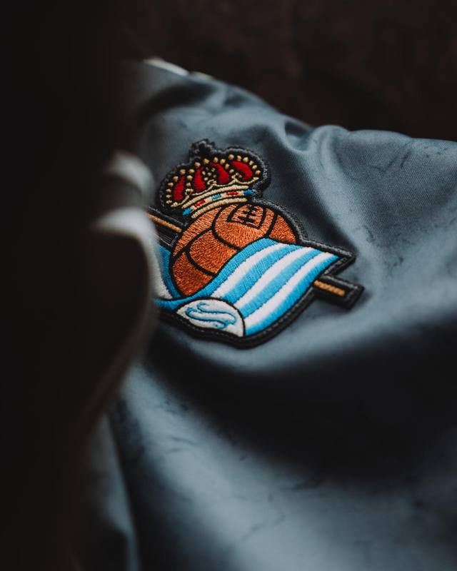 A detailed close-up shot of the Real Sociedad club crest on their 2025/26 away kit.