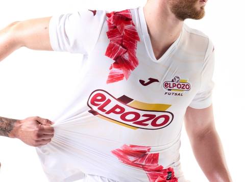 A model wears the white ElPozo Murcia Costa Cálida FS away shirt featuring a red cured ham graphic design on the shoulder and hem.