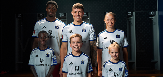 Hamburger SV players and children posing in the locker room wearing the club's white home shirt.